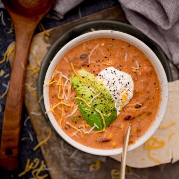 Creamy taco soup in a bowl with avocado slices and sour cream over the top.