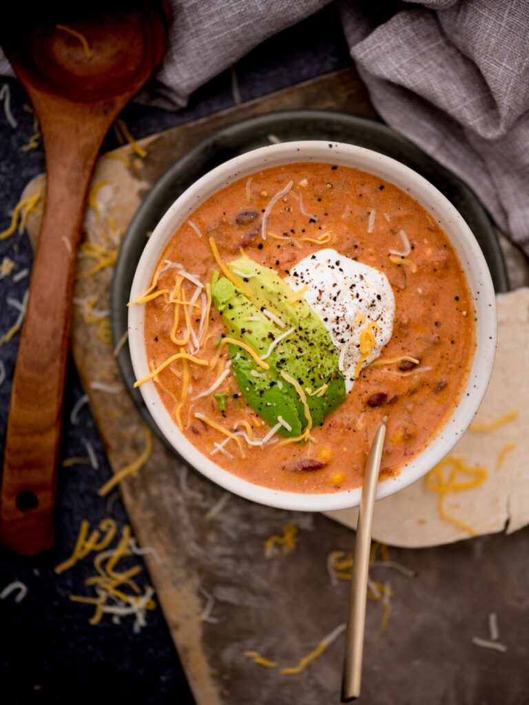 Bowl of creamy taco soup with a dollop of sour cream and avocado slices on top.