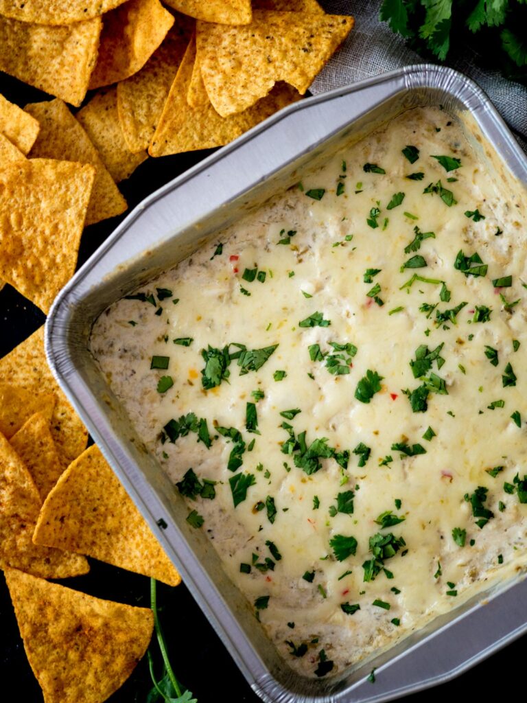Baking dish of queso blanco next to corn tortilla chips.