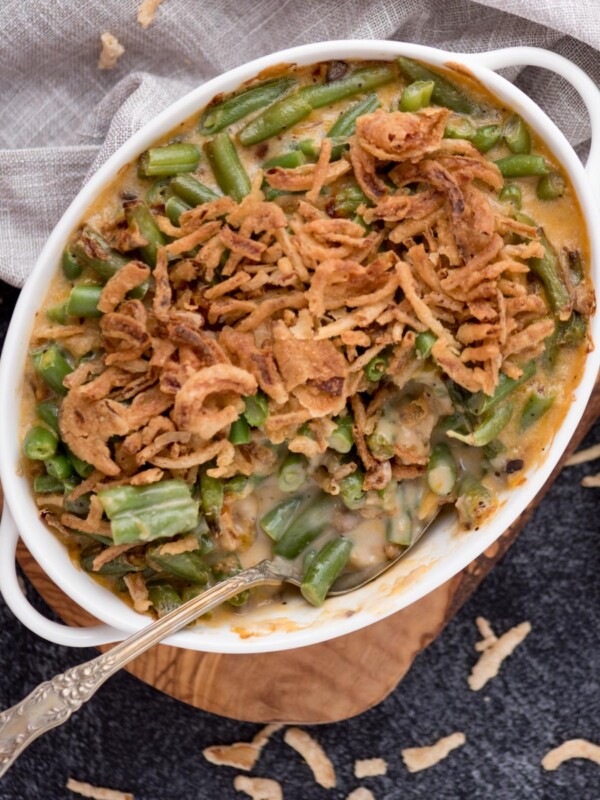 Spoon laying in a baking dish of air fryer green bean casserole topped with french's fried onions.
