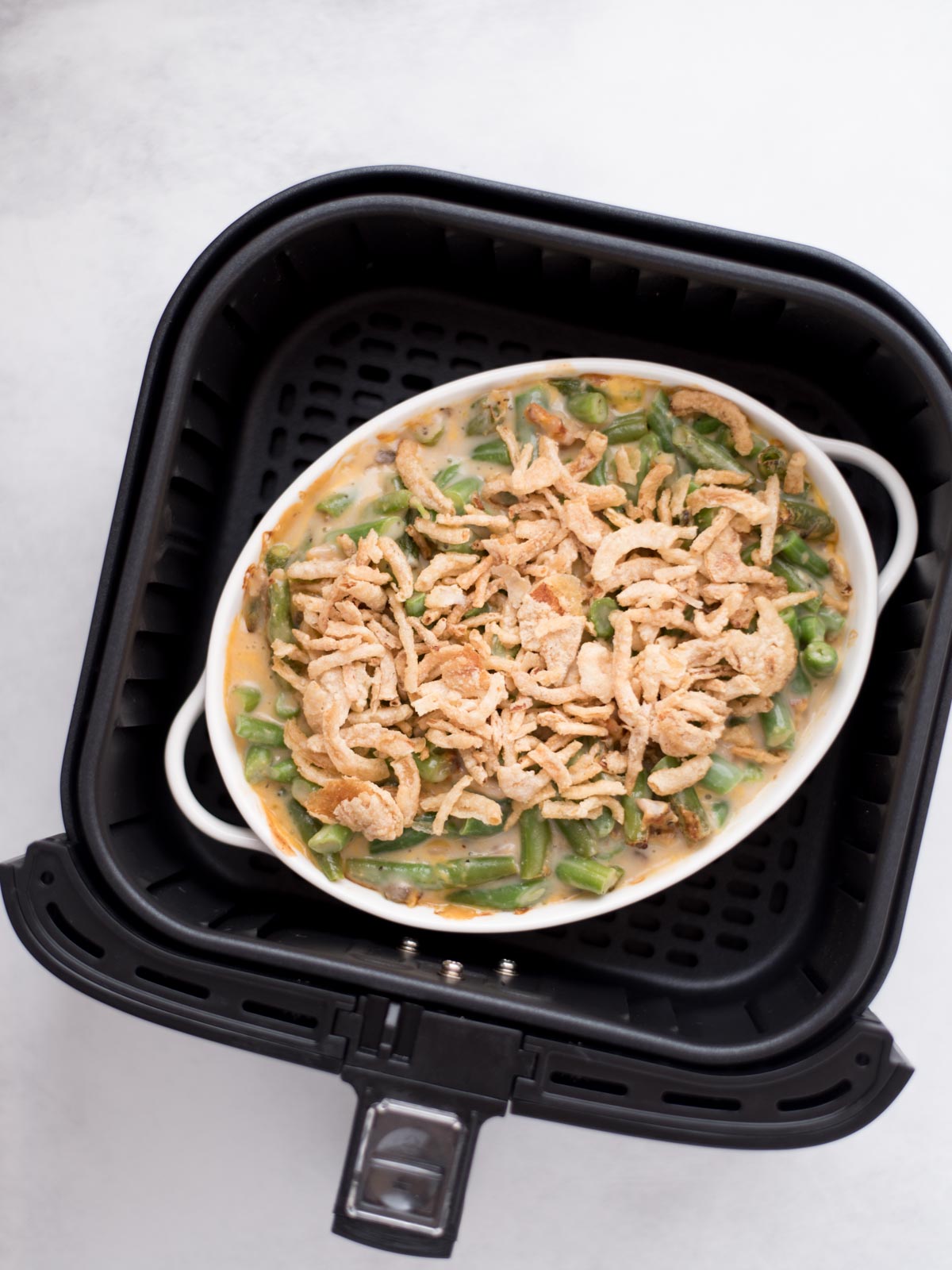 French's fried onions topped over the green bean casserole in the air fryer bucket.