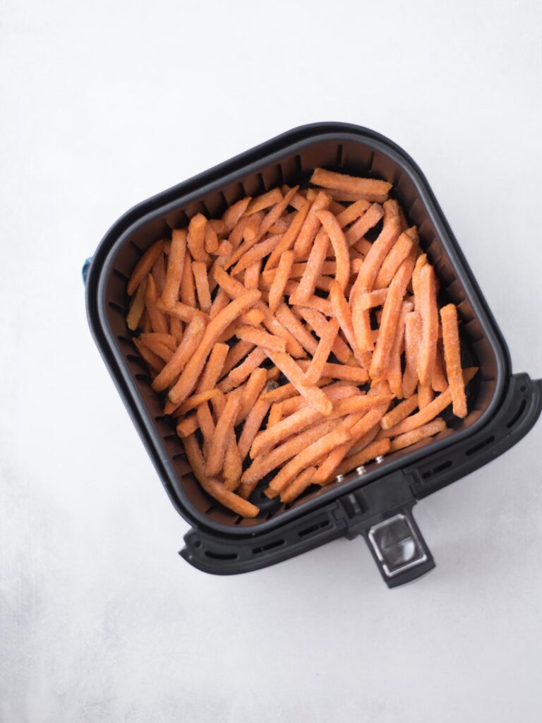 Frozen sweet potato french fries added to the air fryer bucket.