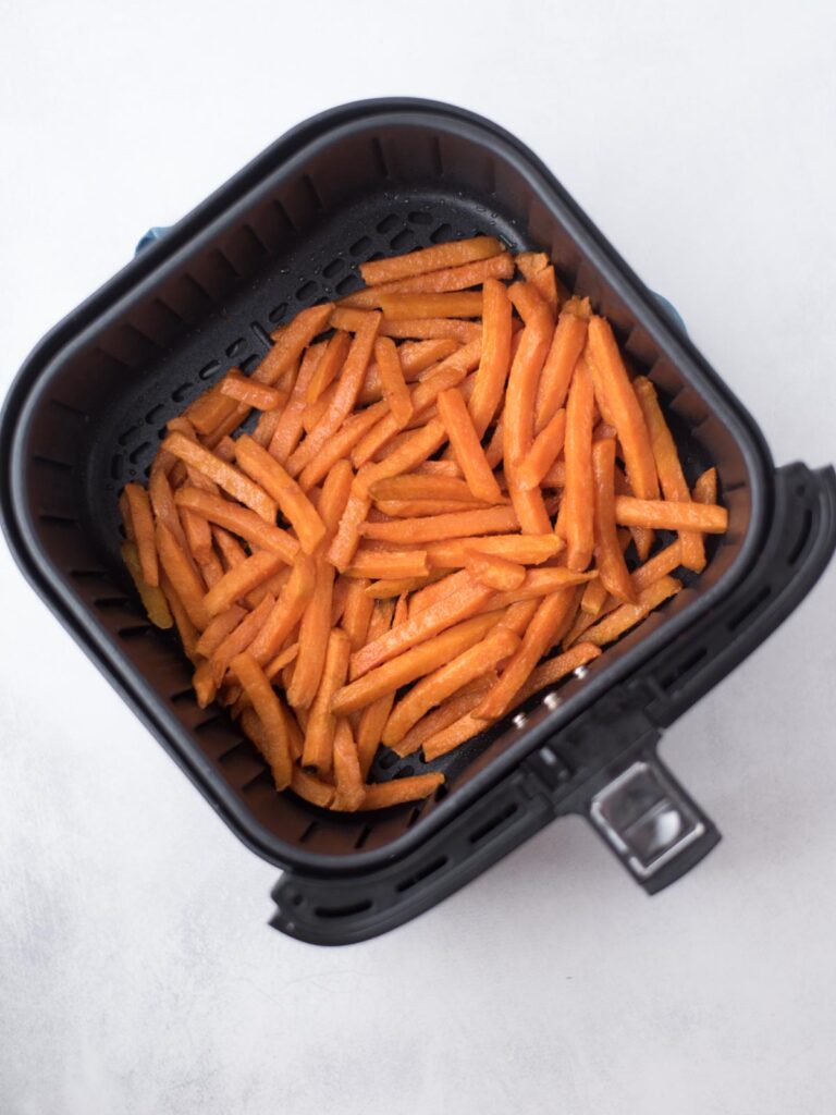 Cooked sweet potato french fries in the air fryer bucket.