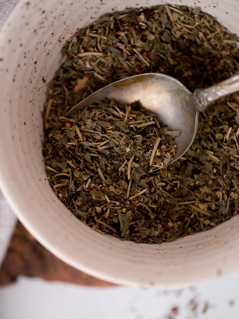 top view of homemade italian seasonings in a bowl with a spoon tucked in.