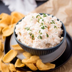 corn dip with cream cheese in a blue bowl surrounded by fritos scoop corn chips