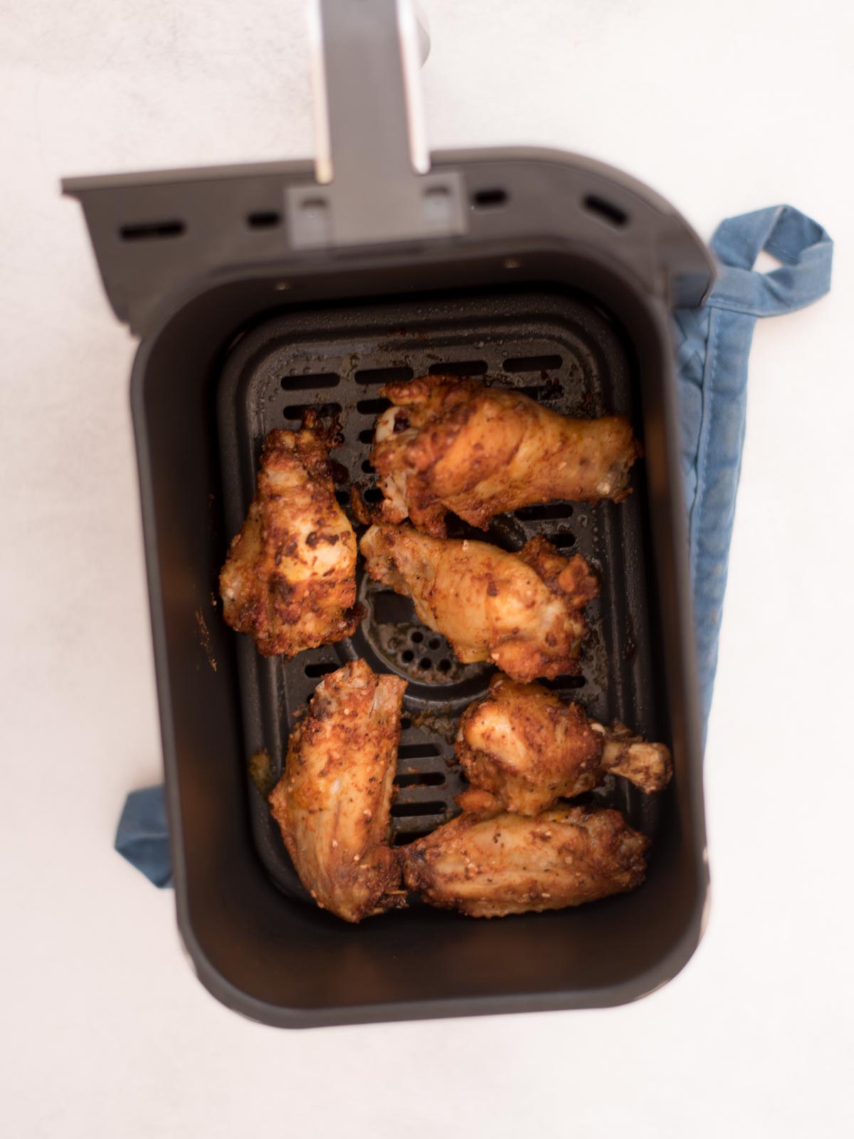 seasoned wings partially cooked inside of an air fryer basket
