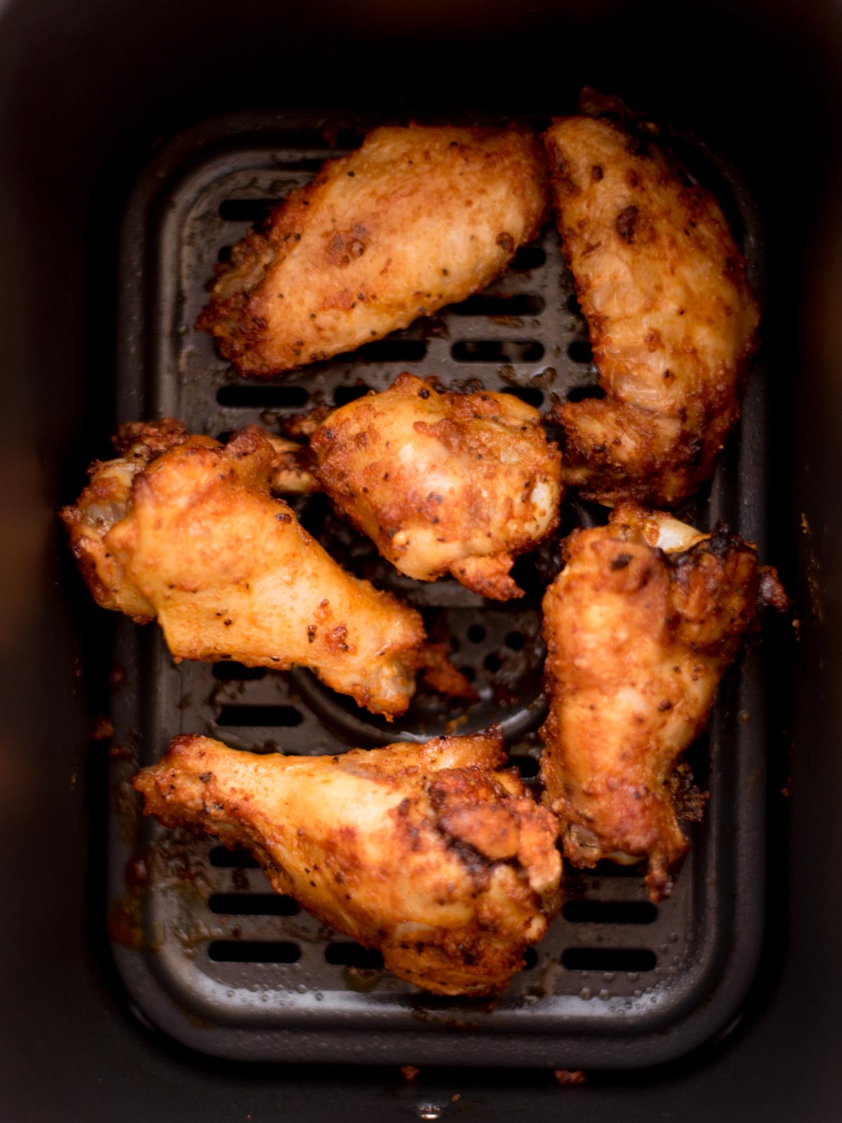 cooked wings inside of an air fryer basket