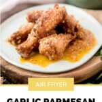 pinterest graphic of garlic parmesan chicken wings stacked on a light blue plate