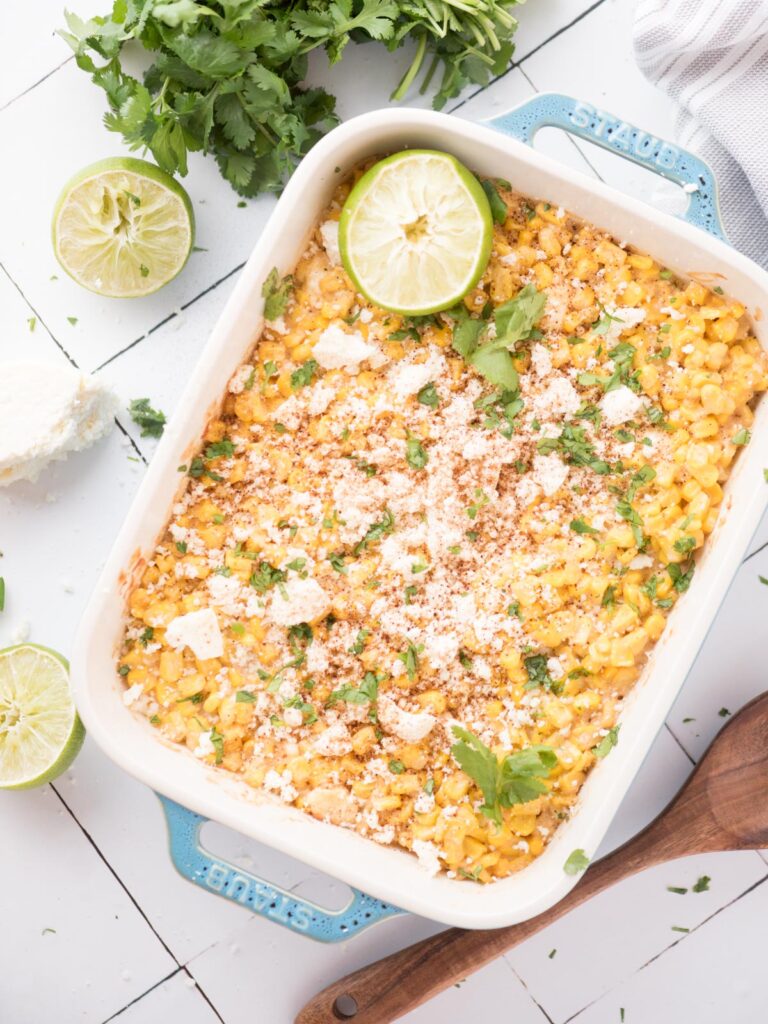 Baking dish mexican street corn casserole with a lime wedge on top.