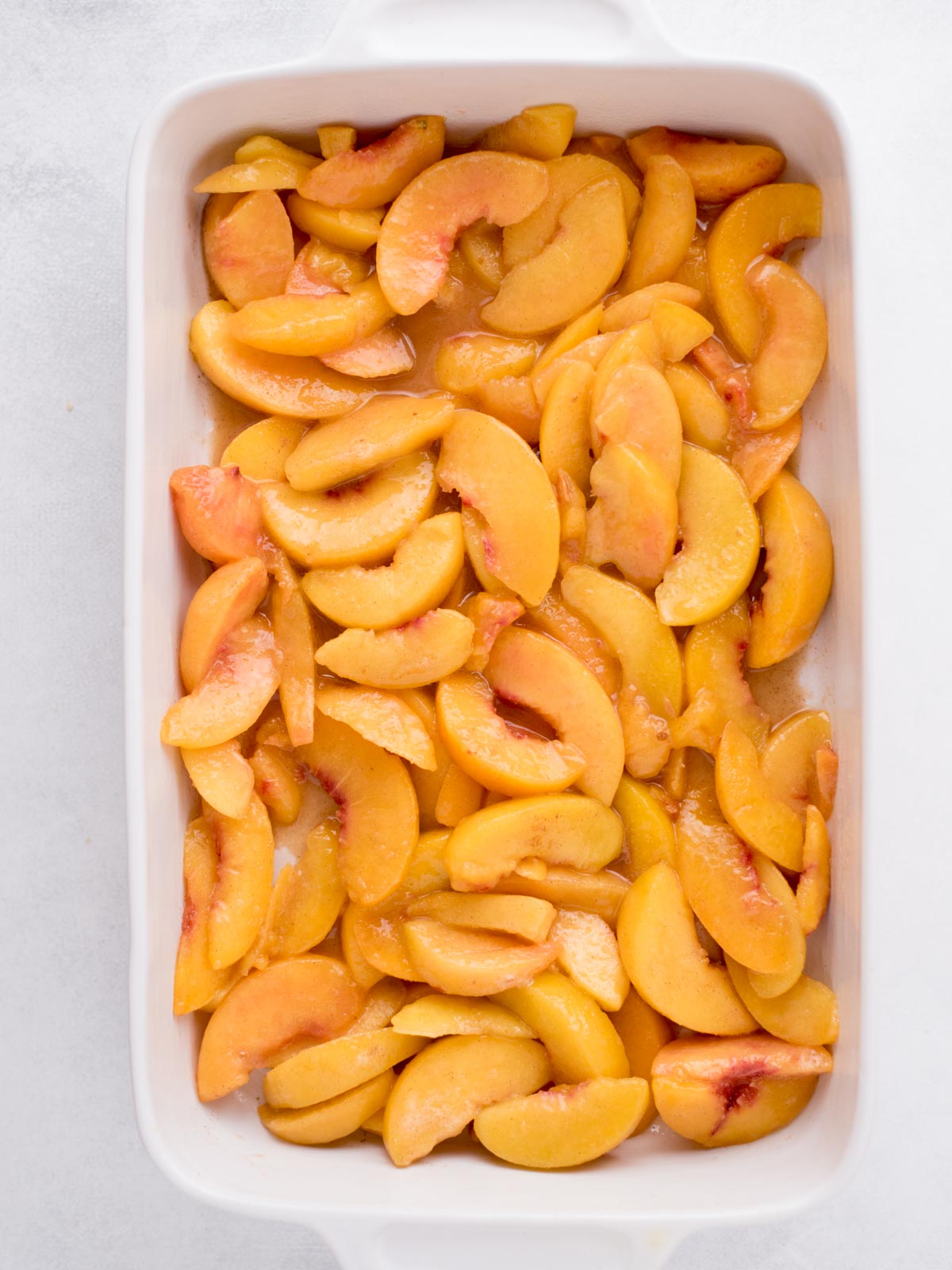 Frozen peaches laying in a baking dish.