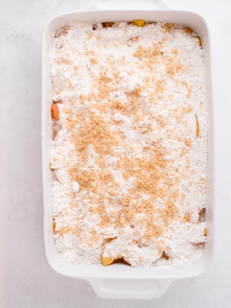 Cake mix and frozen peaches in a baking dish.