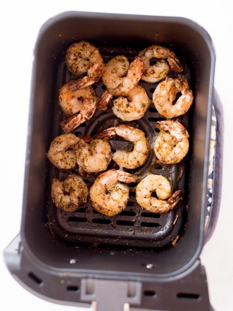 Cooked seasoned shrimp inside an air fryer bucket.