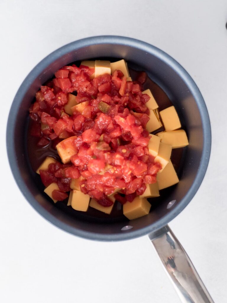 Diced tomatoes and velveeta cubed in a saucepan.