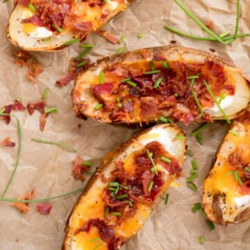 Air fryer loaded potatoes with sour cream, bacon and cheese, garnished with chopped chives ready to serve.