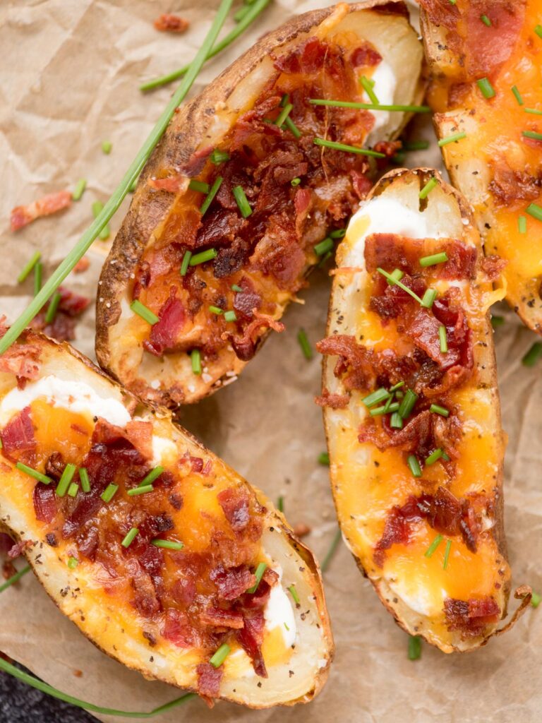 Cheese, bacon and chive loaded potato skins on parchment paper ready to enjoy.