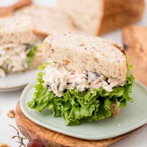 Half chicken salad with lettuce sandwich on a small plate.