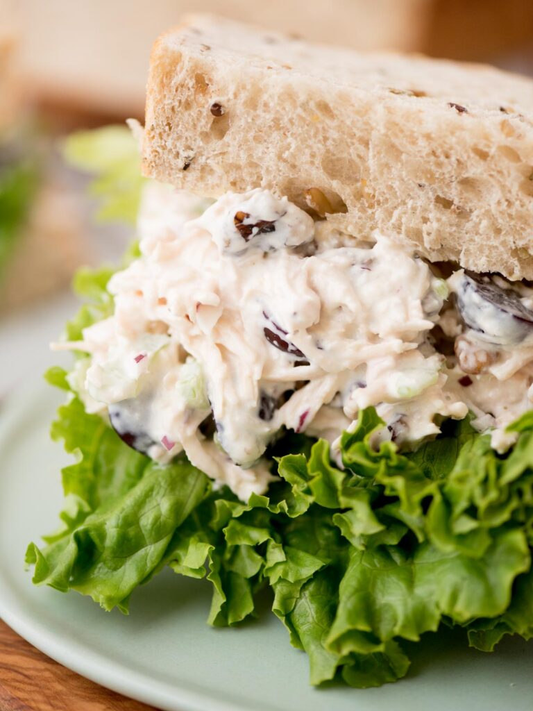 Creamy chicken salad on lettuce and wheat bread served on a plate.