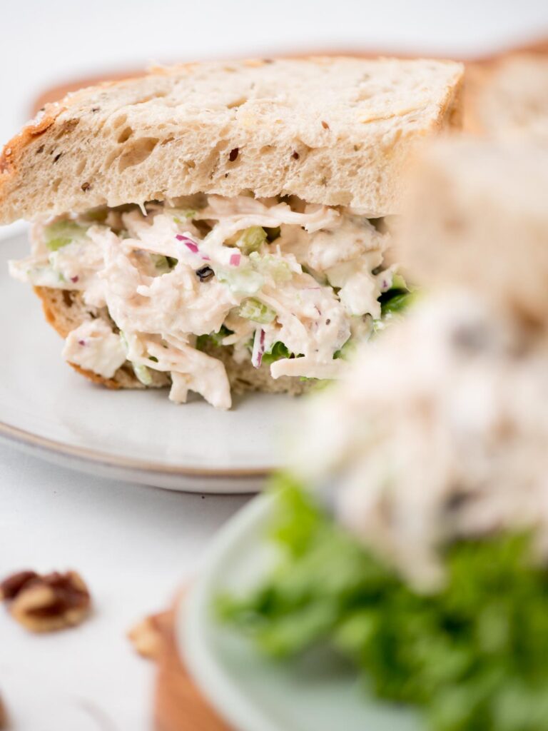 Partial view of a chicken salad sandwich on wheat bread.