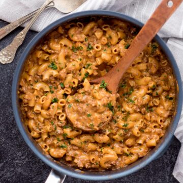 Skillet of homemade hamburger helper with a wooden spoon resting in it.