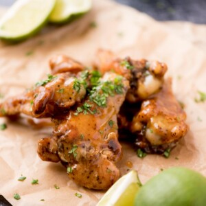 Close up of tequila lime wings with chopped cilantro garnished on top laying on parchment paper.