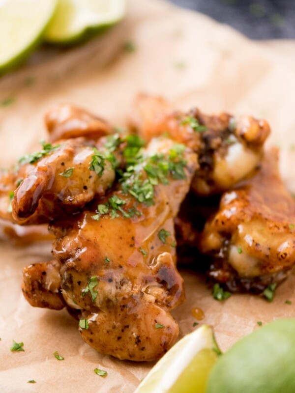 Close up of tequila lime wings with chopped cilantro garnished on top laying on parchment paper.