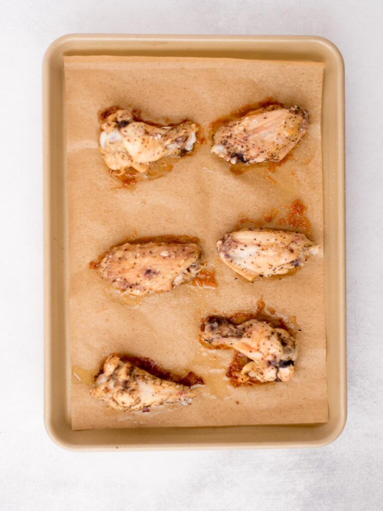Seasoned chicken wings on a baking sheet.