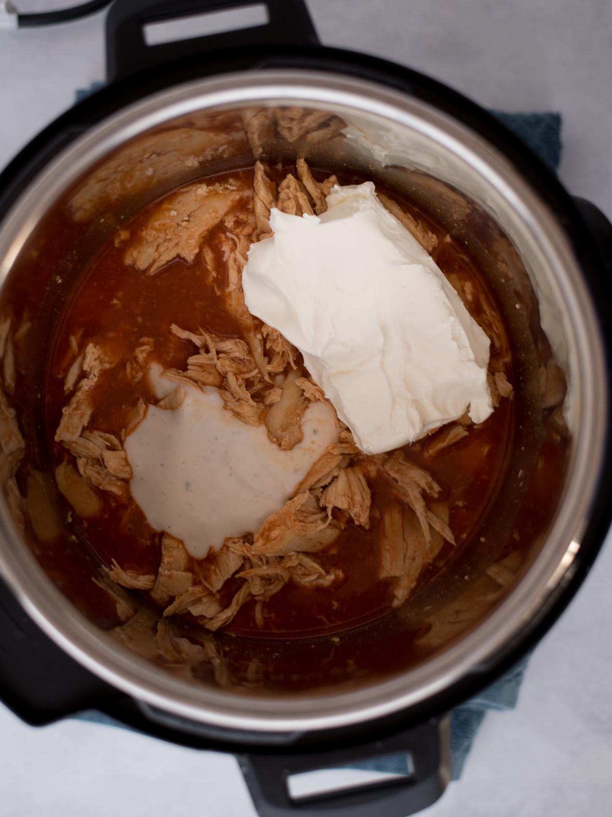 Instant pot filled with ingredients for buffalo chicken dip, ready to cook.