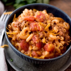 american goulash in a bowl topped with shredded cheese