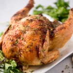 whole roasted chicken on a plate with fresh parsley