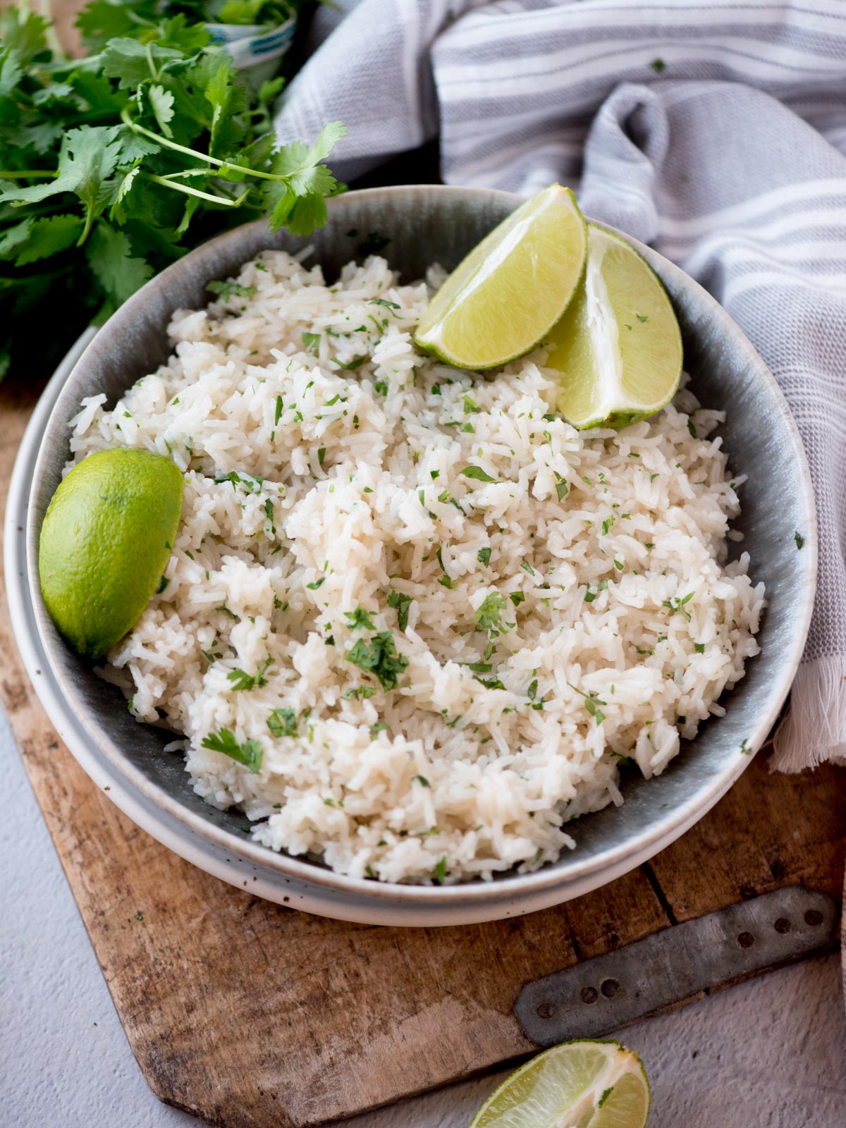 cilantro lime rice in a bowl topped with chopped cilantro and lime wedges