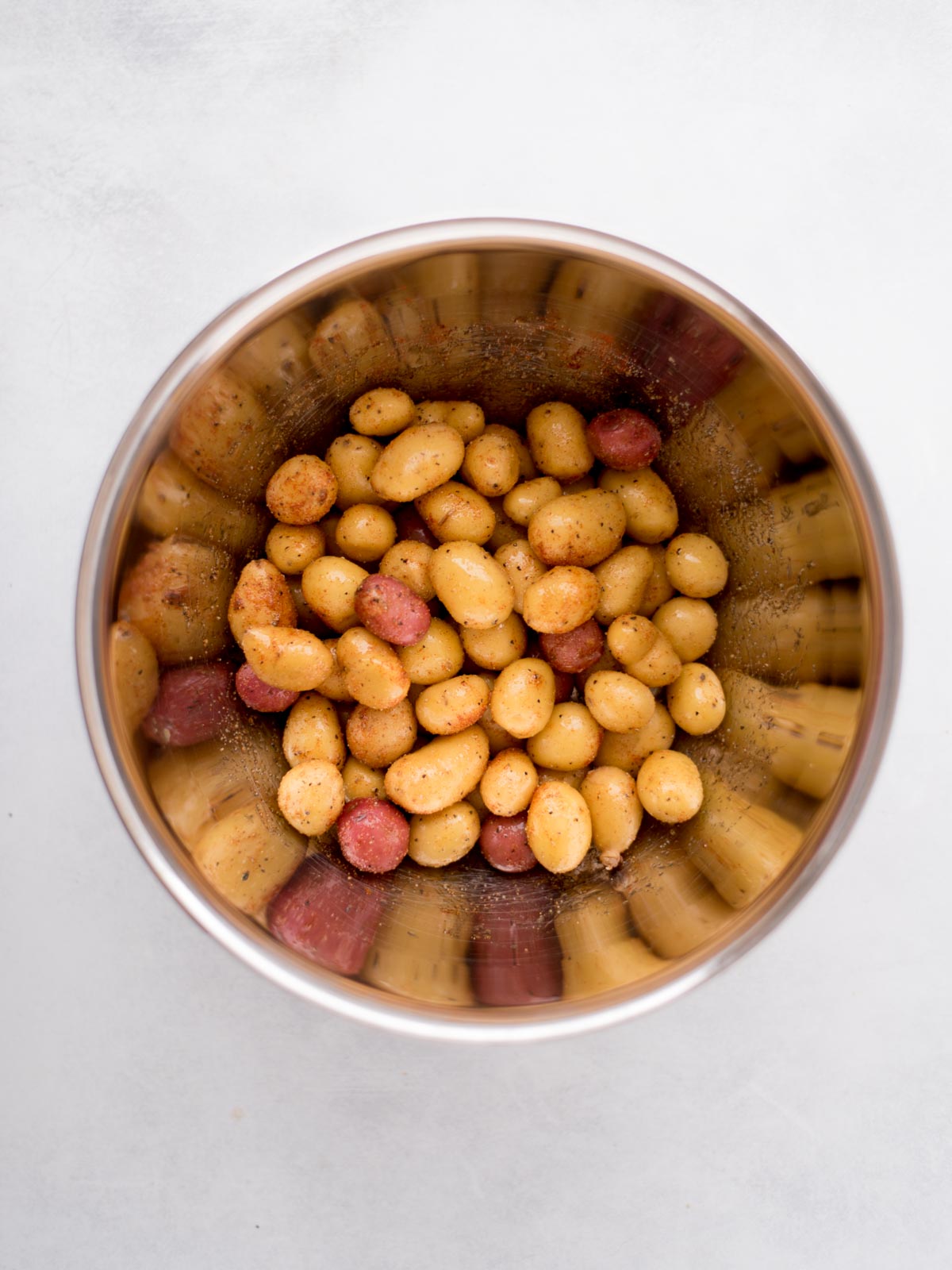 seasoned uncooked baby potatoes in a mixing bowl