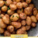 pinterest image of air fried baby potatoes in a bowl topped with fresh parsley. The potatoes are in a bowl surrounded by fresh parsley and a kitchen towel. It has a text overlay that says "air fryer baby potatoes"