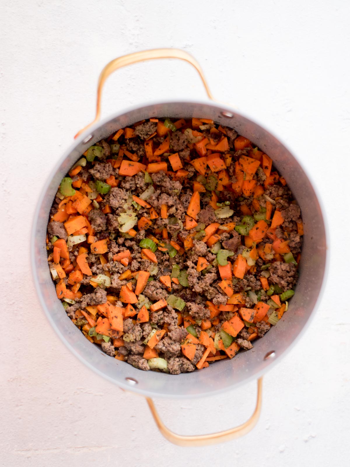 cooked seasoned ground beef in a pot with carrots and celery