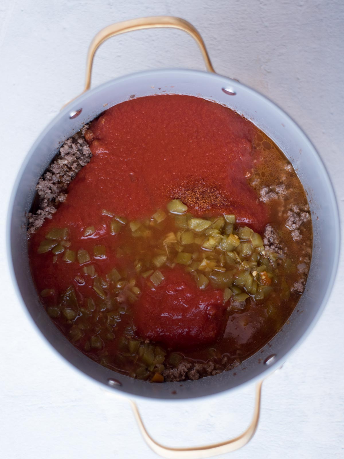 cooked ground beef along with tomato sauce, green chiles, and water in a stock pot