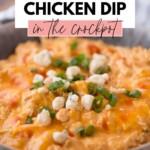 buffalo chicken dip in a serving bowl topped with sliced green onions and blue cheese with a text overlay that says buffalo chicken dip in the crockpot
