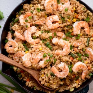 shrimp fried rice in a skillet with a wooden spoon