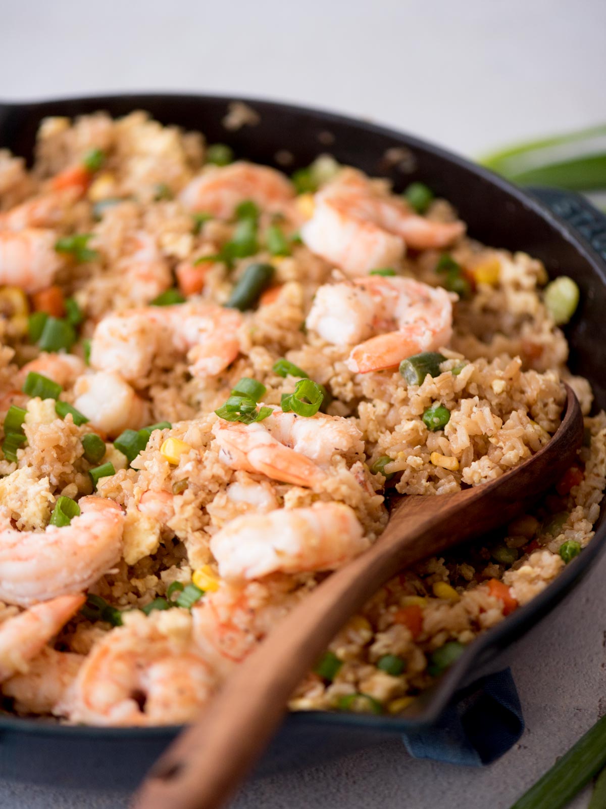 shrimp fried rice in a skillet with a wooden spoon
