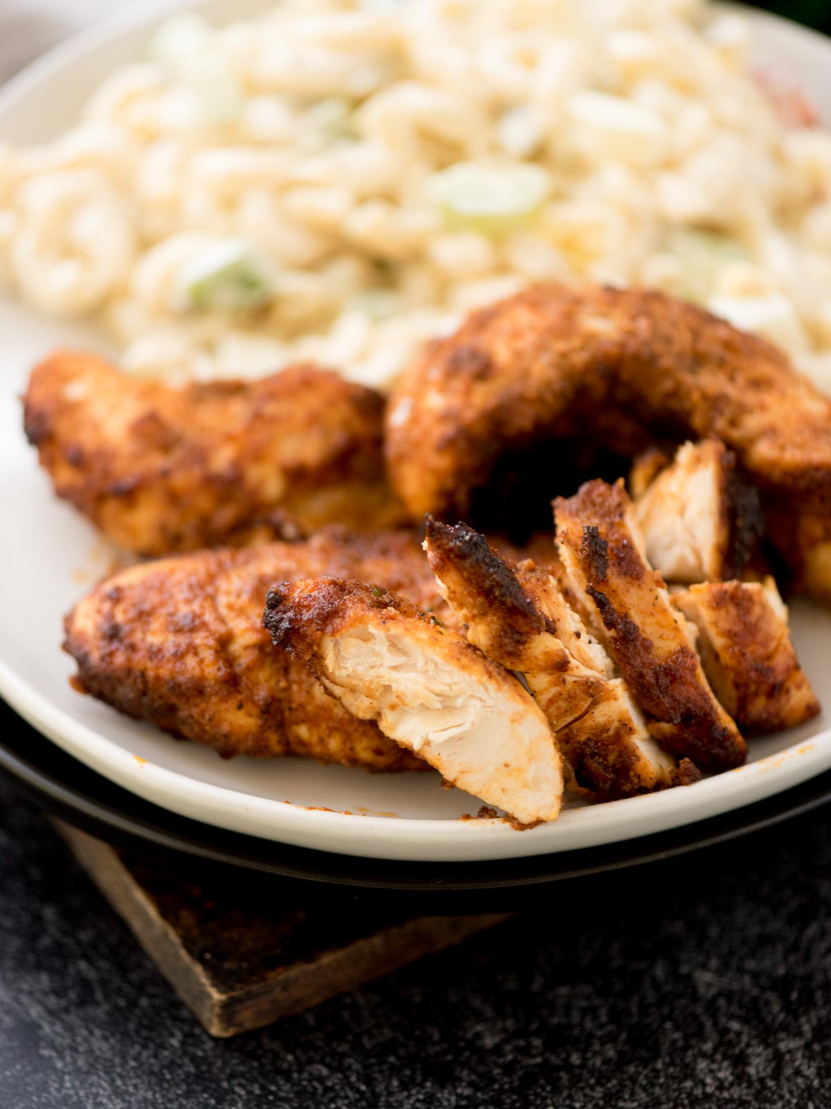 air fried chicken tenderloins on a plate with macaroni salad. Some of them are whole and some are sliced.