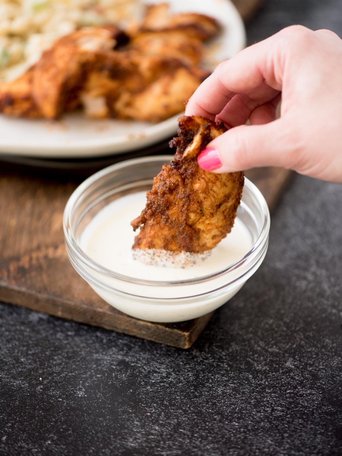 air fried chicken tenderloin being dipped in a bowl of ranch