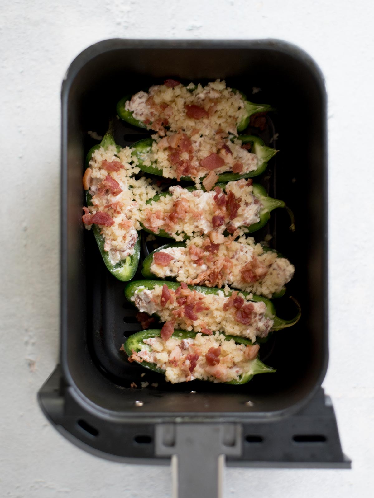 uncooked jalapeno poppers in an air fryer basket
