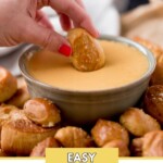 soft pretzel bite being dipped in beer cheese in a bowl. The bowl is surrounded by pretzel bites. There is a text overlay that says "Easy beer cheese dip"