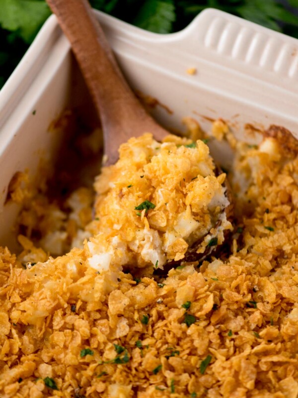 baking dish with funeral potatoes being scooped out with a wooden spoon