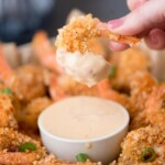 crispy shrimp being dipped in bang bang sauce in a small bowl