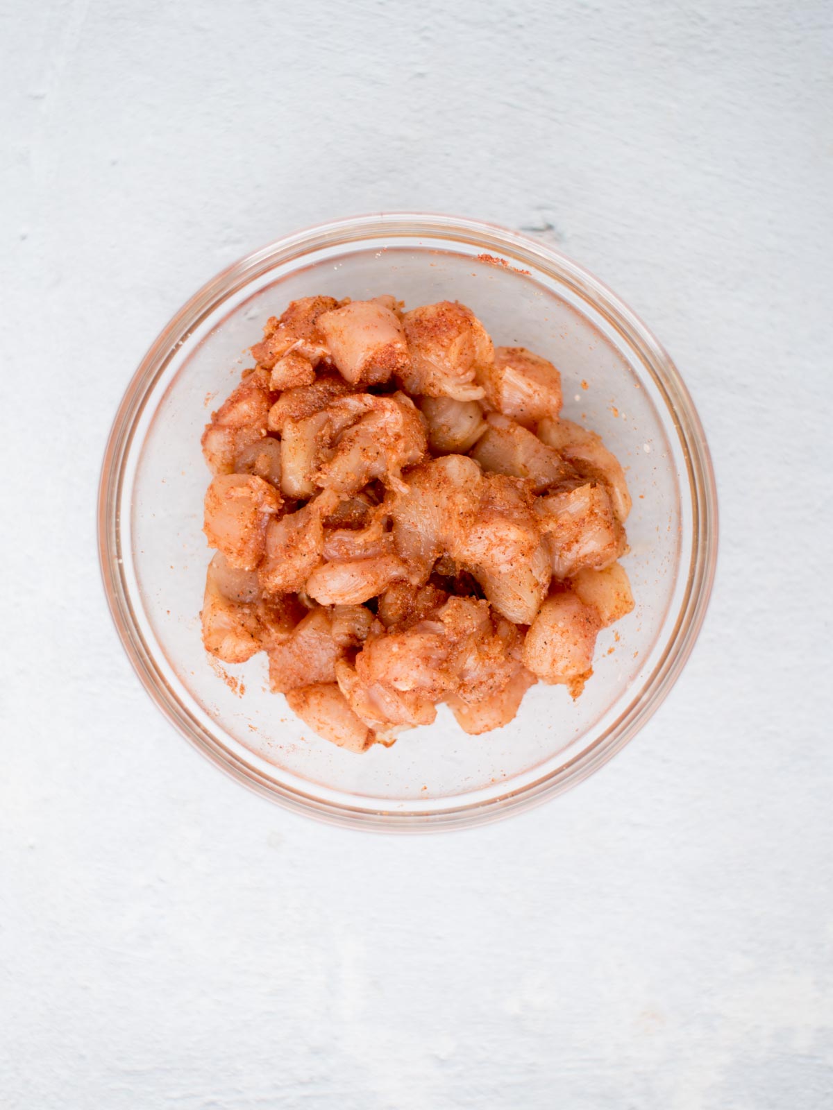 Seasoned raw diced chicken pieces in a mixing bowl.