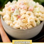 Macaroni salad in a grey bowl surrounded by a serving spoon and fresh parsley. There is text on the screen that says "Southern Macaroni Salad".