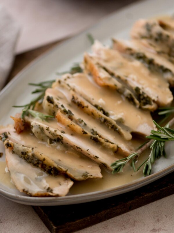 oven roasted turkey breast sliced and on a platter surrounded by fresh rosemary