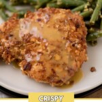 A plate with crispy almond-coated chicken drizzled with sauce, served alongside green beans. The top of the image has text that says sweetlysplendid.com, and the bottom has a yellow banner with the text Crispy Almond Chicken.