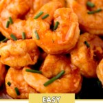 Close-up of buffalo shrimp garnished with chopped chives, showcasing a vibrant orange color and spicy glaze. Text on top reads sweetlysplendid.com and at the bottom reads Easy Buffalo Shrimp.
