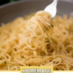 Close-up of a fork twirling homemade lemon garlic pasta over a bowl. The pasta is garnished with herbs. The image has a text overlay at the top with sweetlyspendid.com and at the bottom with Homemade Lemon Garlic Pasta.