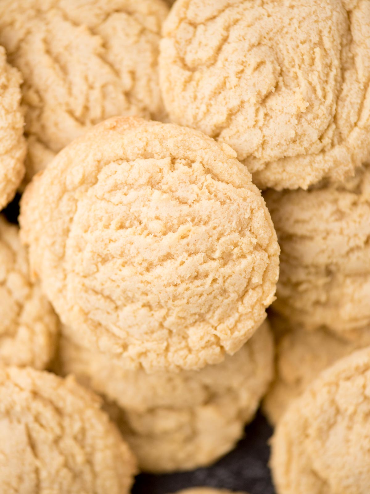 A close-up view of several golden, crinkled pudding mix cookies stacked together, showing their soft, crumbly texture.